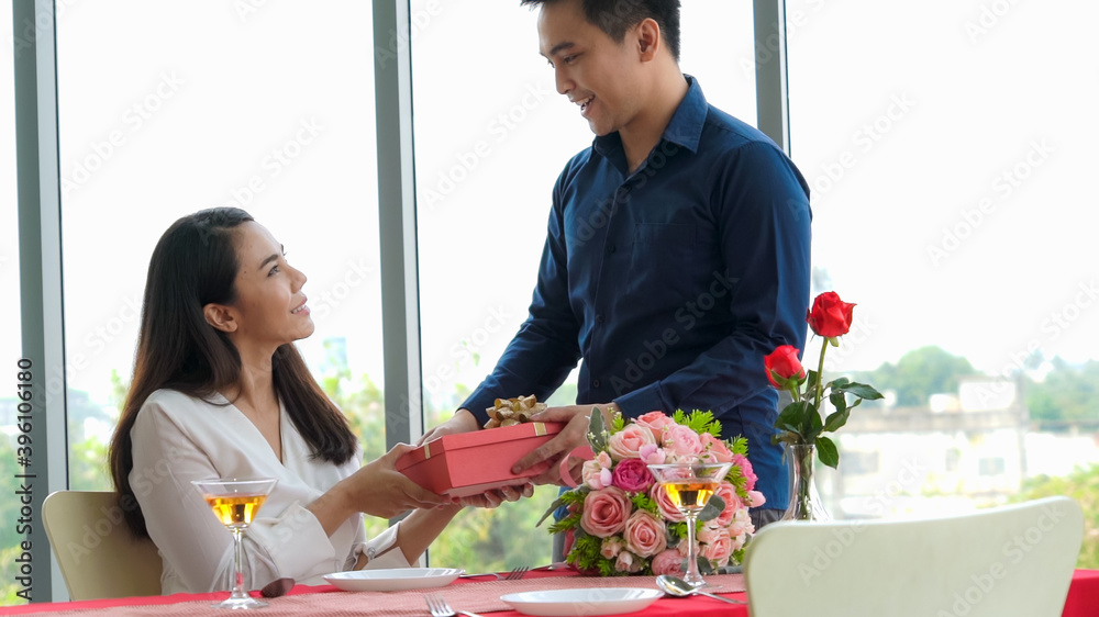 Romantic couple giving gift to lover at restaurant . Happy couple lifestyle .