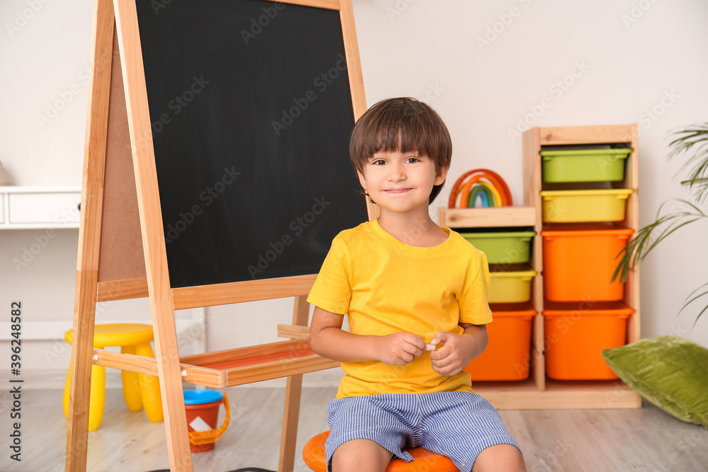 Cute little boy near blackboard in kindergarten