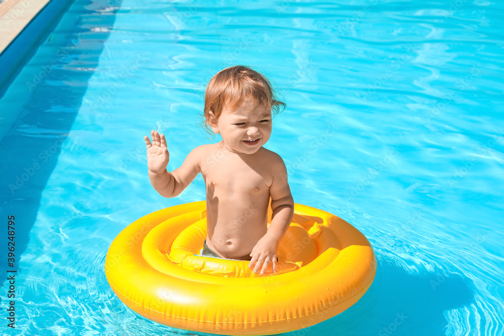 Cute baby boy with inflatable ring in swimming pool