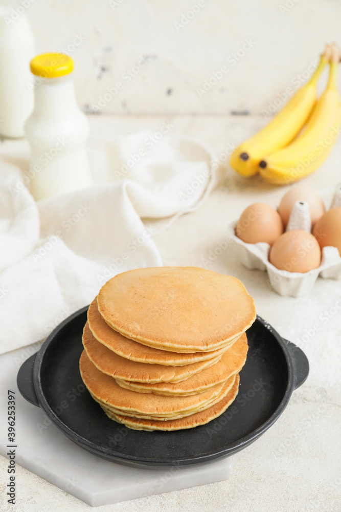 Frying pan with tasty banana pancakes on table