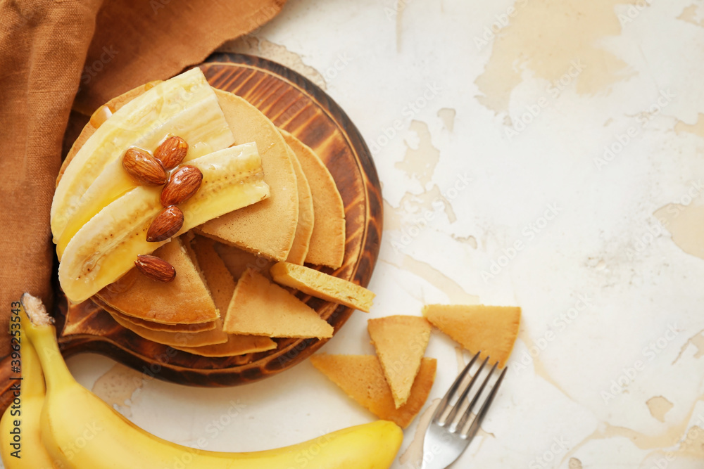 Board with tasty banana pancakes on white background