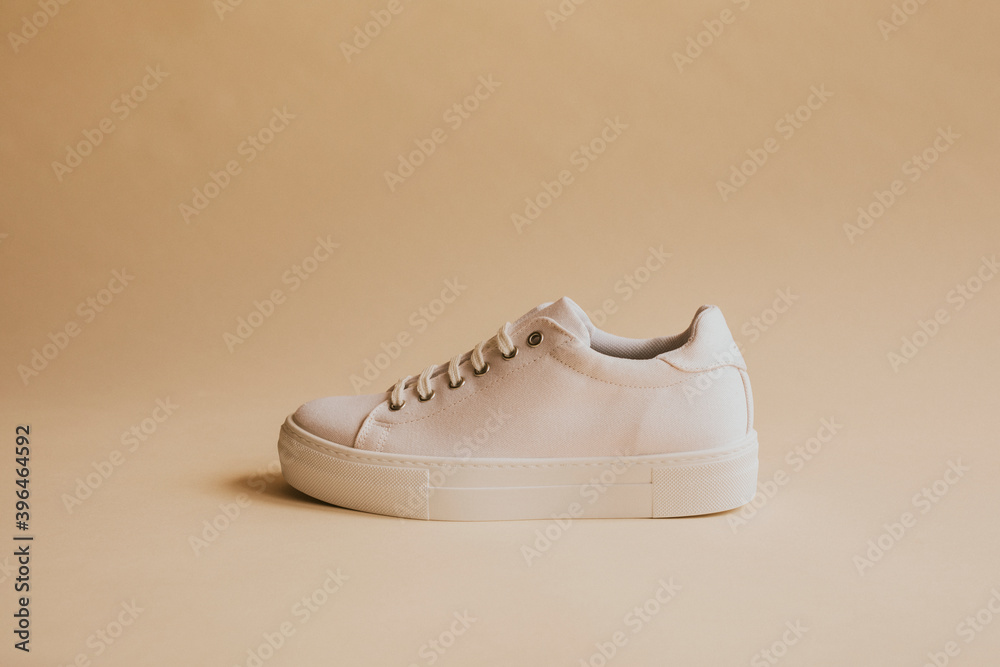 Single white canvas sneakers on beige