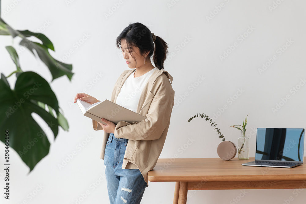 Asian woman leaning on a wooden table while reading a book