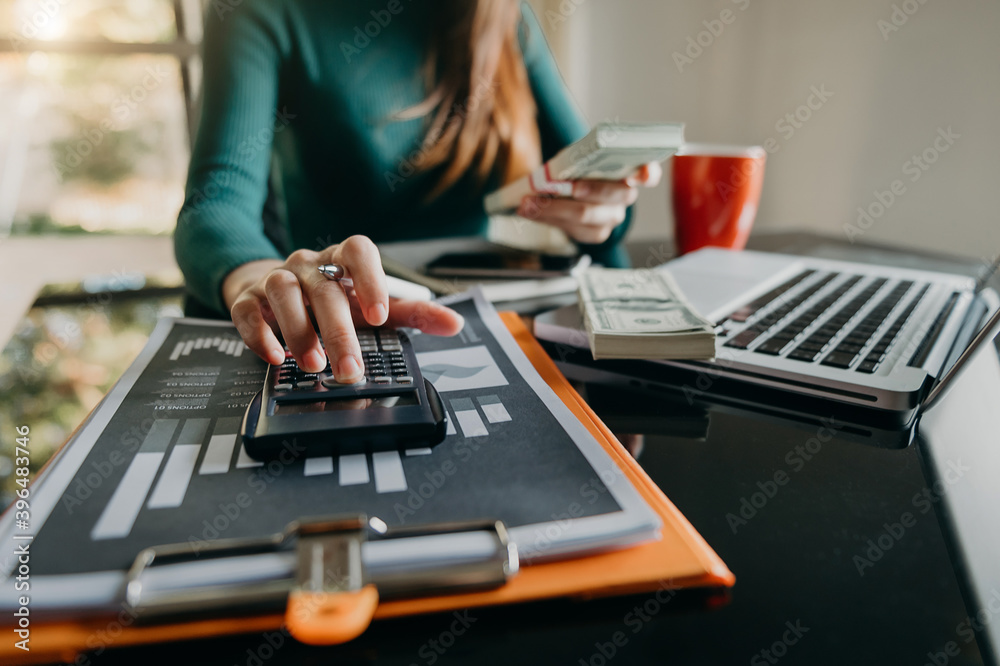 businessman working on desk office with using a calculator to calculate the numbers, finance account