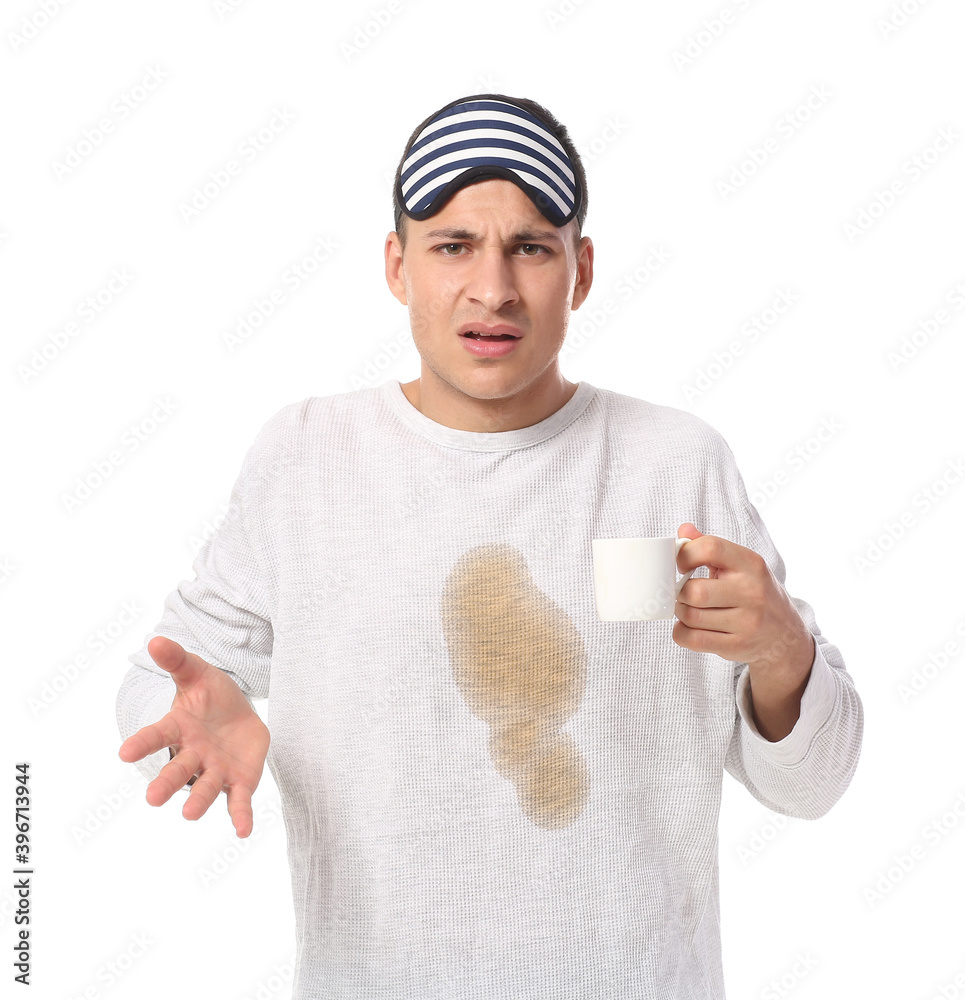 Stressed young man with coffee stains on his pajama top on white background