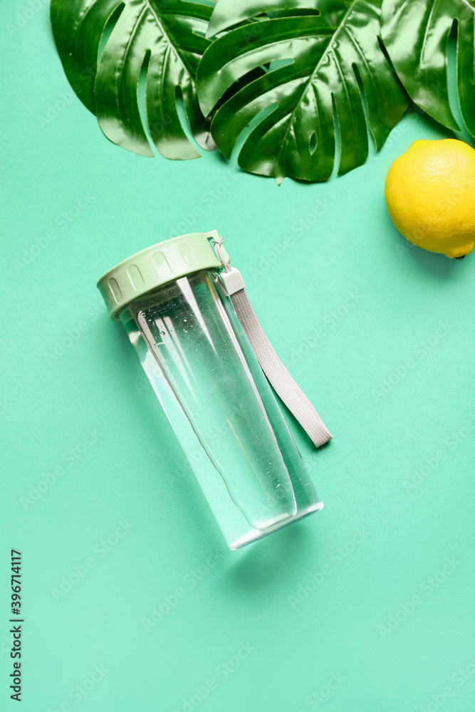 Bottle of water and lemon on color background