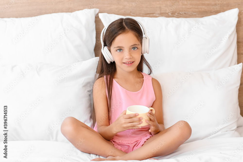 Cute little girl listing to music in bed