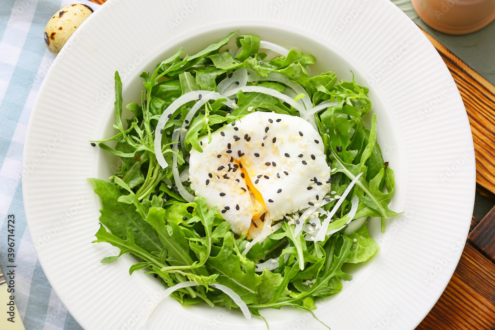 Plate with tasty arugula salad on wooden table