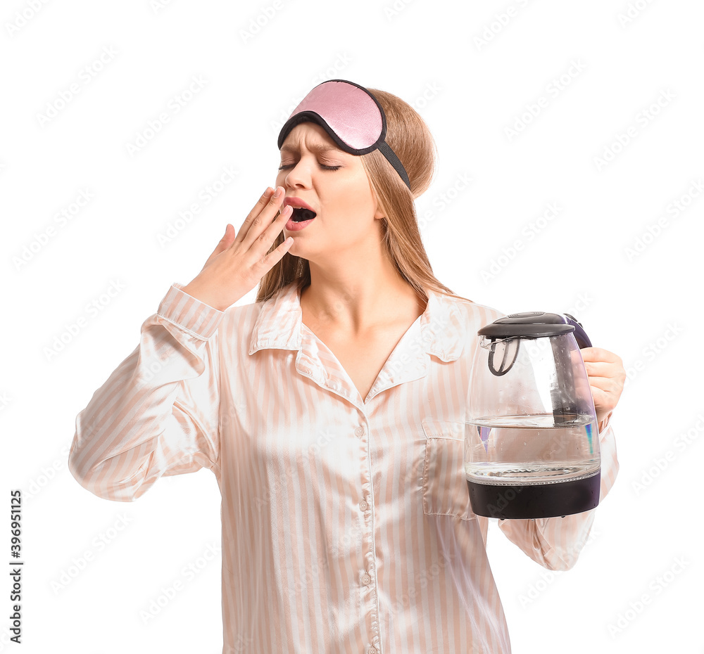 Exhausted woman in pajamas holding electric kettle on white background