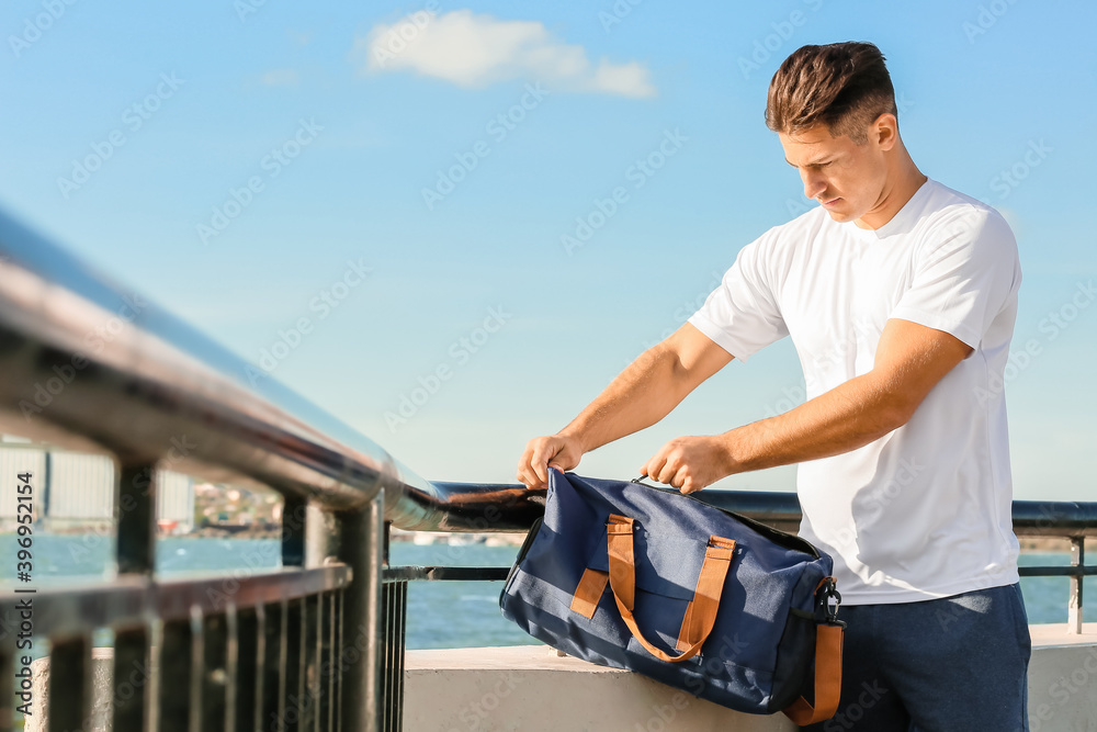 Sporty young man with bag outdoors