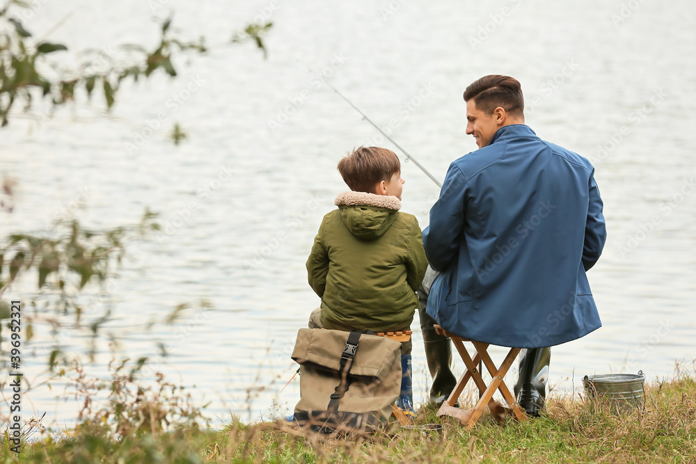 Little boy and his father fishing on river