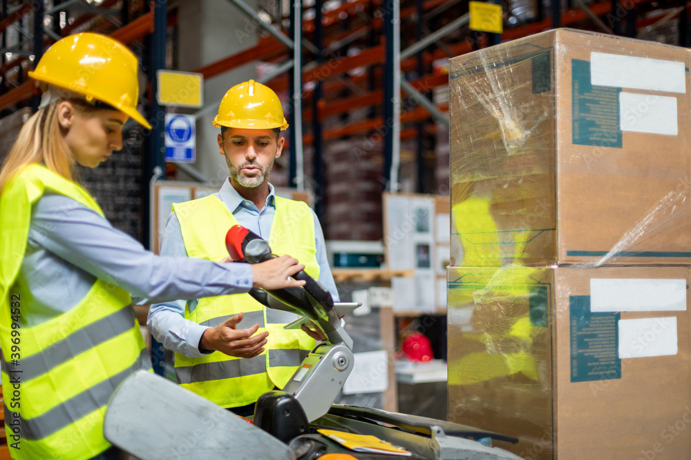 Female warehouse worker learns how to use forklift with instructor