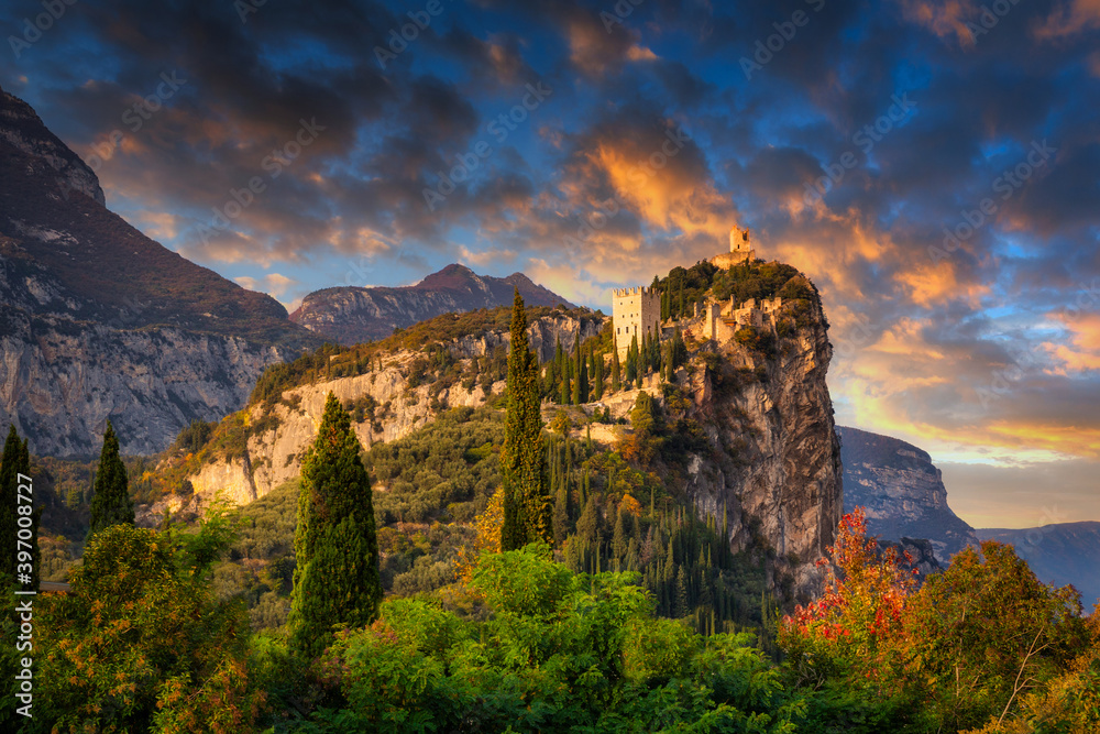 Amazing ruins of Arco Castle on the cliff in northern Italy at sunset.