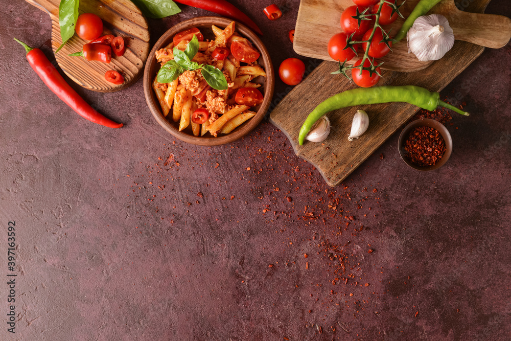 Bowl of penne pasta with tomato sauce on color background