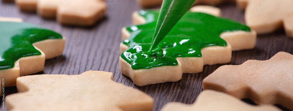 Close up of drawing Christmas tree sugar cookie on wooden table background with icing.