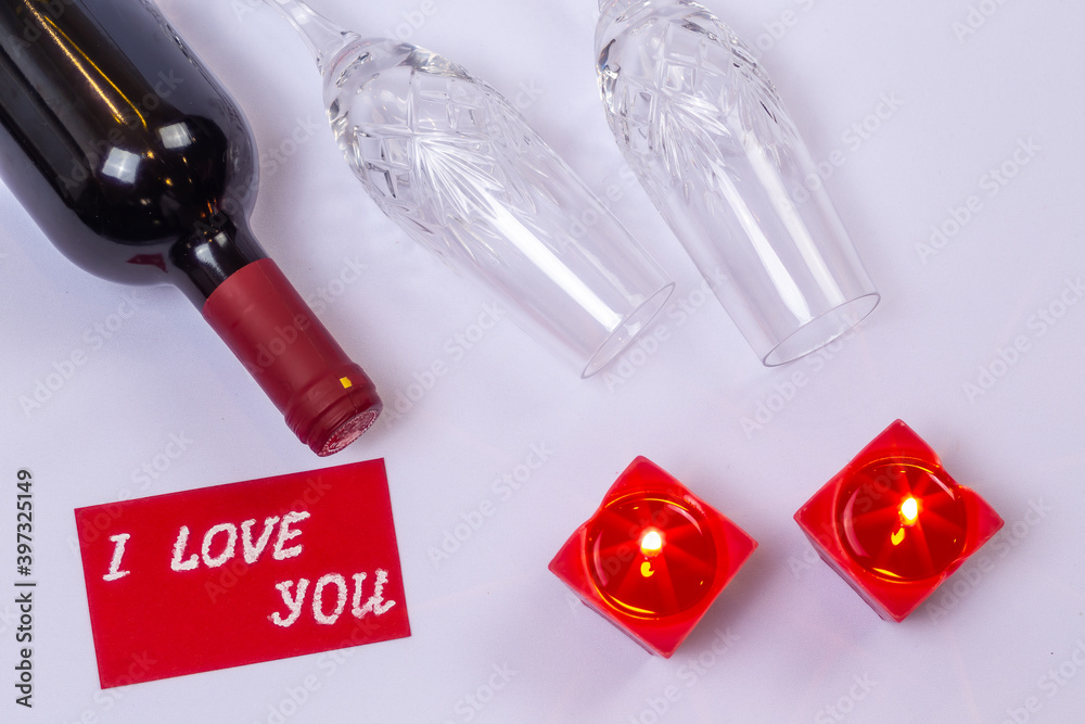 Red wine, chocolate and candles on white background.