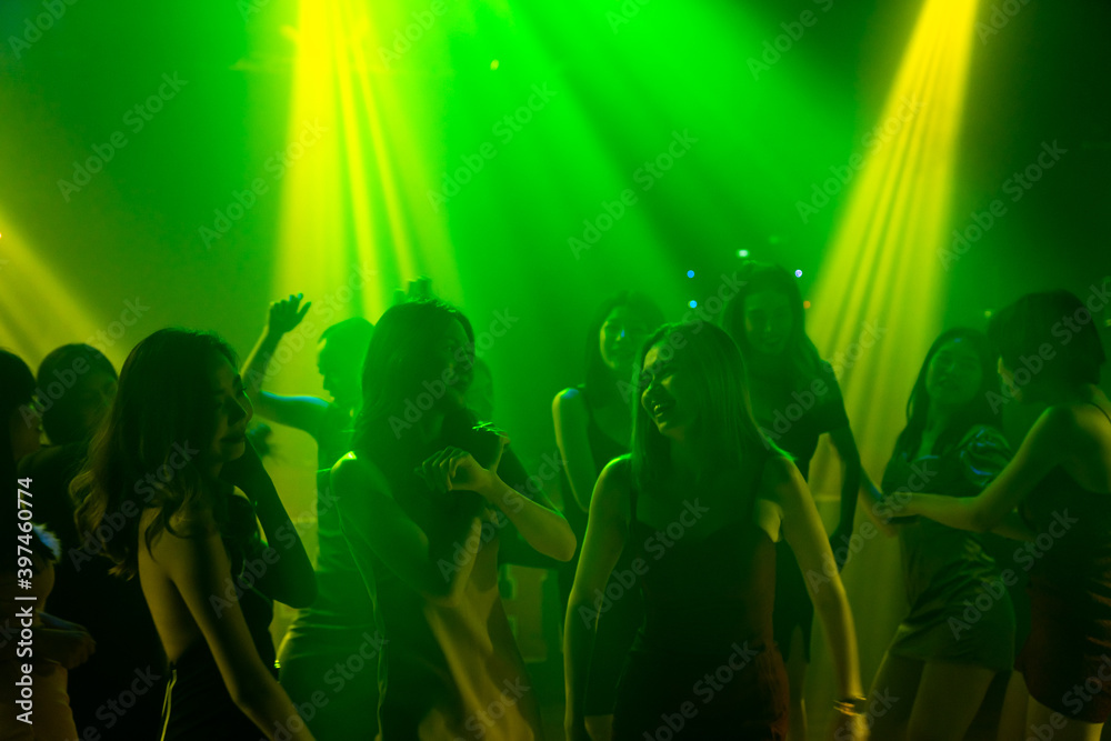 Silhouette image of people dance in disco night club to music from DJ on stage . New year night part