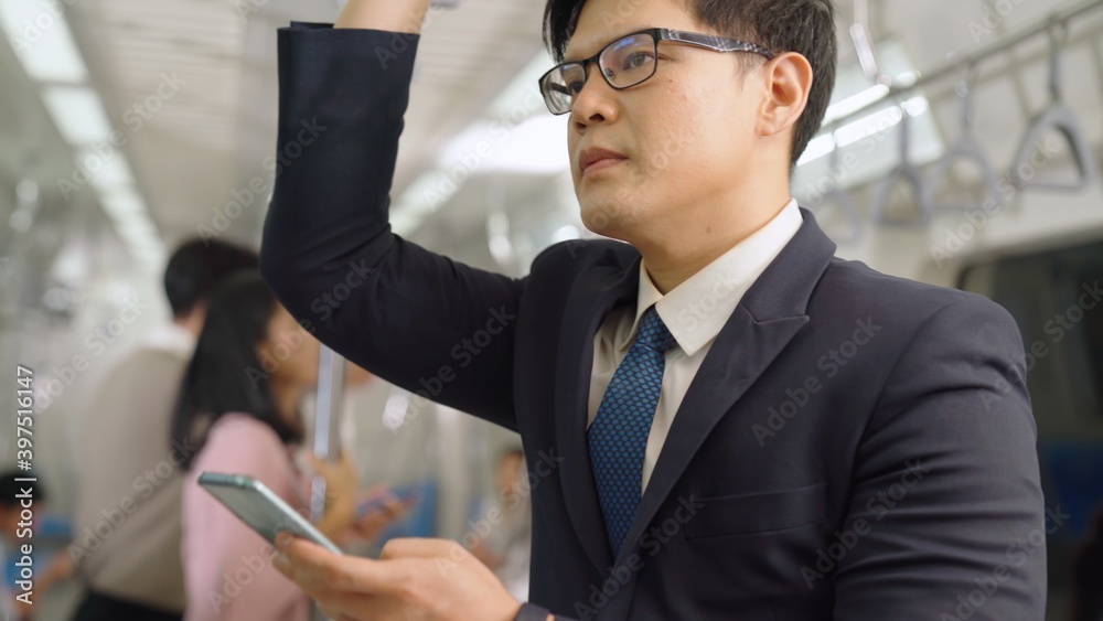 Businessman using mobile phone on public train . Urban city lifestyle commuting concept .