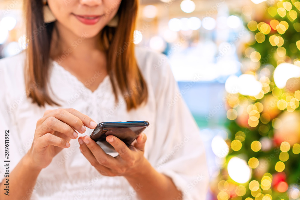 Young woman using smart phone and looking for online shopping promotion during the Christmas season 