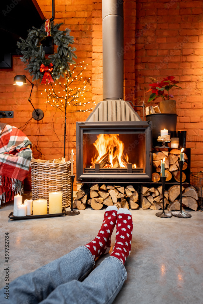 Woman in Christmas socks by the fireplace at home. The concept of comfort during winter and New Year