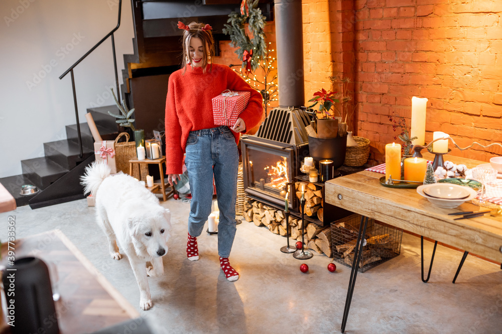 Young woman with her cute dog preparing for a New Year holidays by the fireplace and dining table at