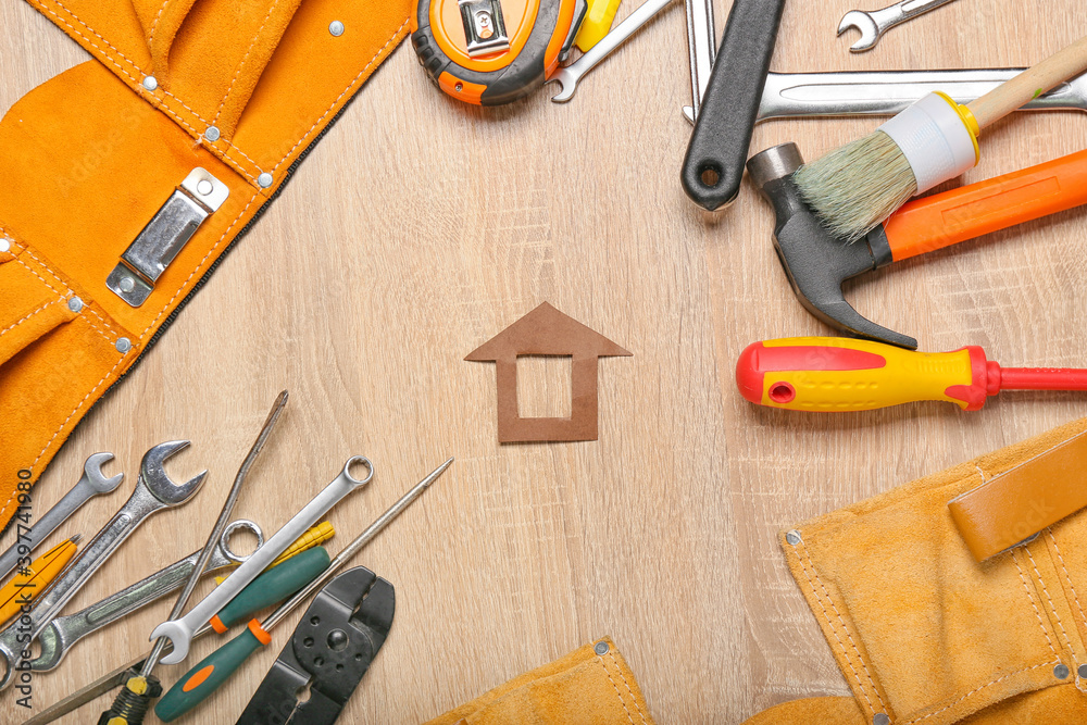 Model of house with supplies on wooden background