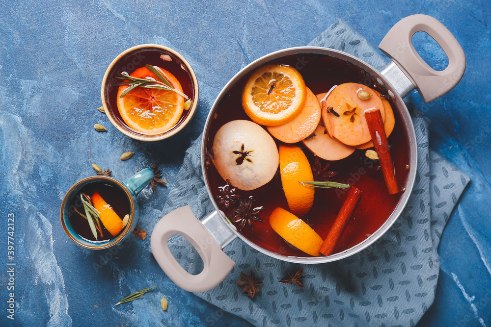 Saucepan with hot mulled wine on color background