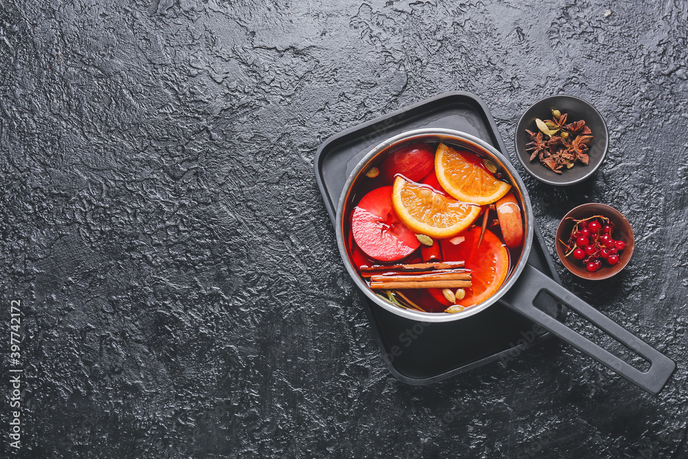 Saucepan with hot mulled wine on dark background