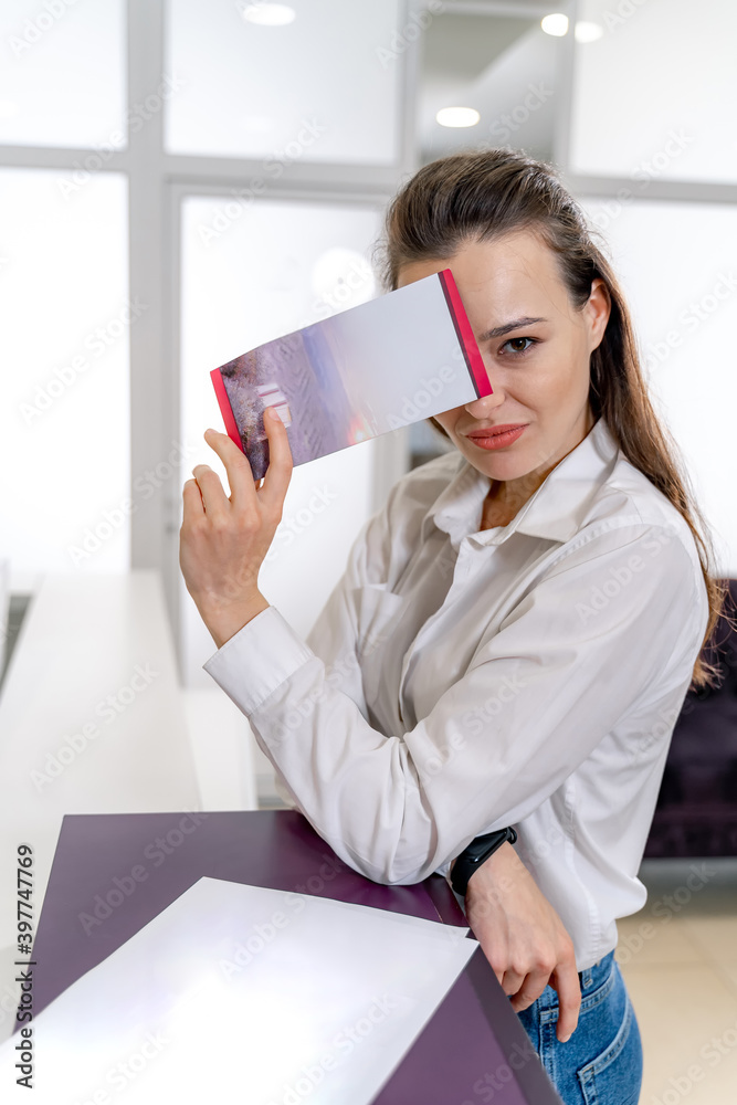 Girl with brochure at the reception. Customer in spa. Woman`s beauty concept. Brunette woman standin