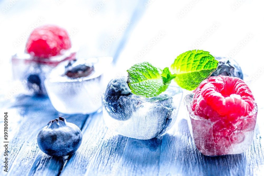 cubes of berry ice and mint leaf on wooden table beckground