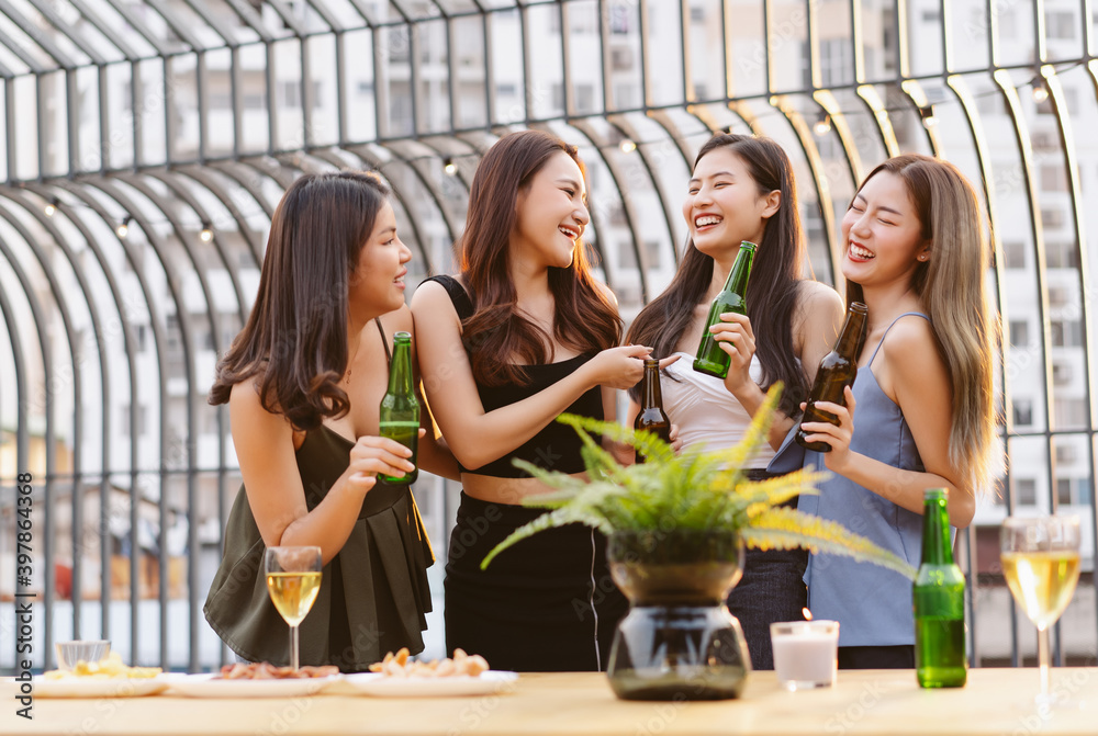 亚洲女孩们一边喝啤酒一边享受屋顶酒吧派对。一群朋友在terr玩得很开心