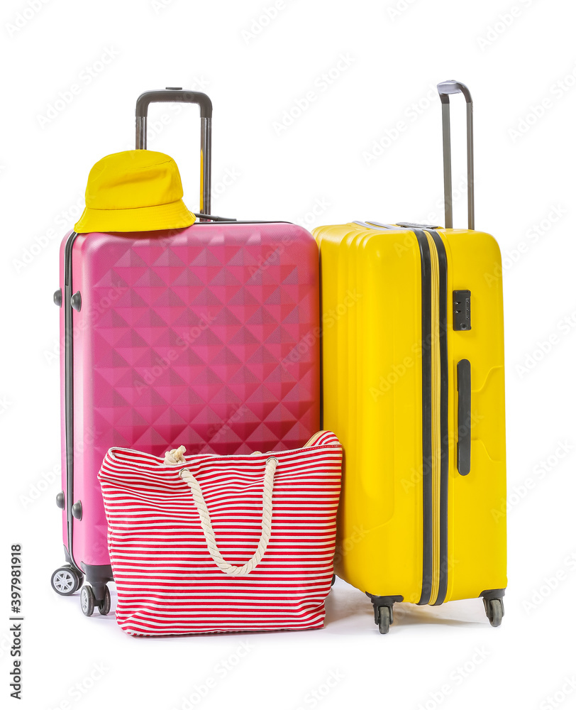 Packed suitcases with hat and bag on white background