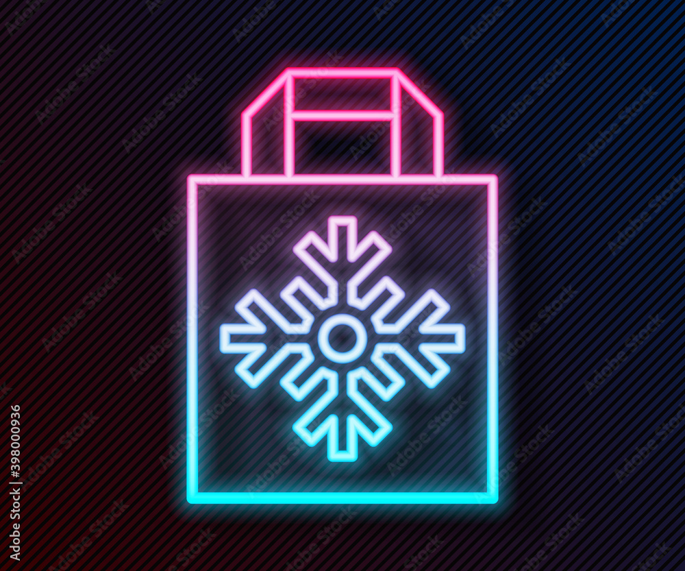 Glowing neon line Christmas paper shopping bag with snowflake icon isolated on black background. Pac