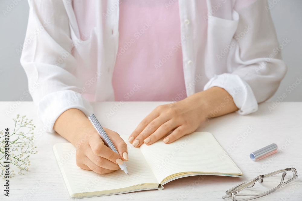 Woman writing in notebook with pen