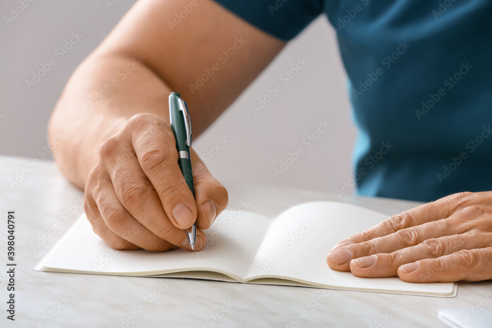 Man writing in notebook with pen