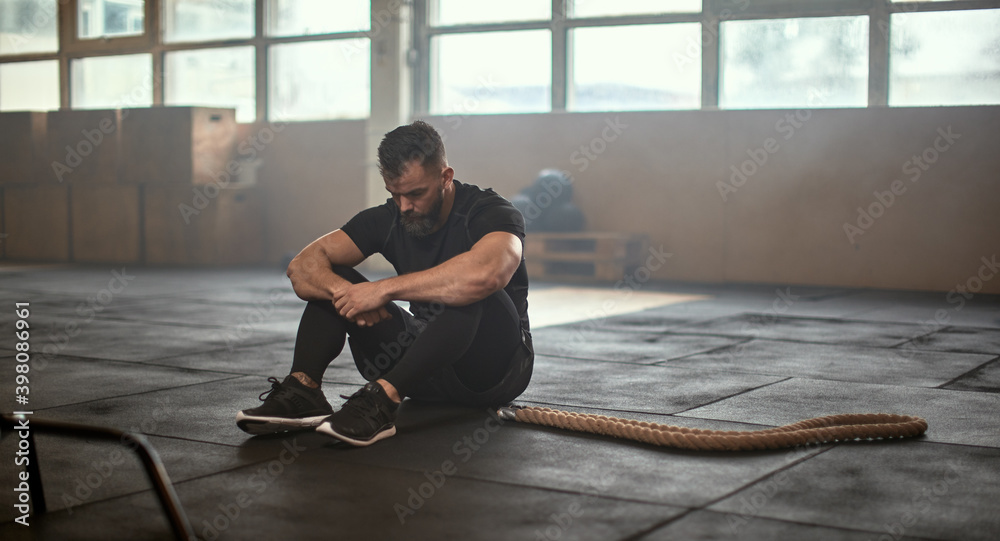 强壮的大胡子男运动员在绳索附近休息