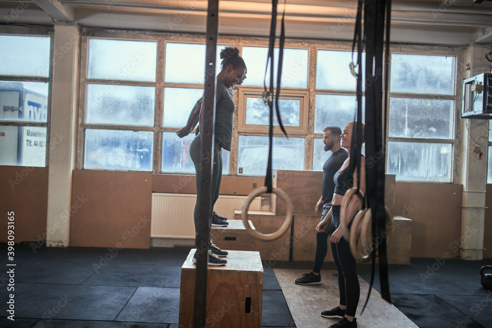 Fit people doing box jumps together in an exercise class