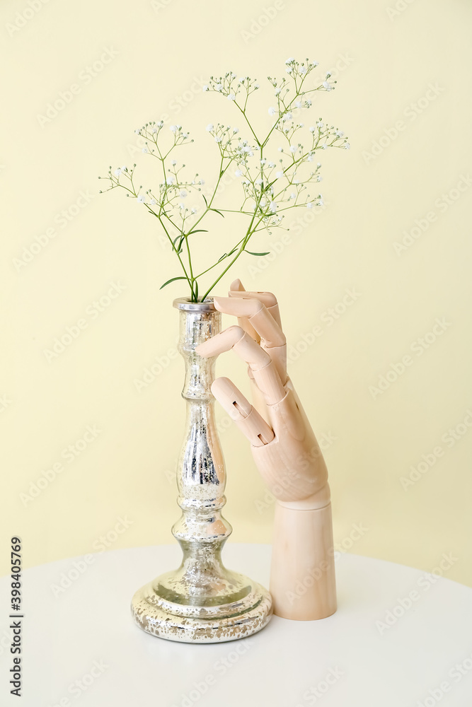 Wooden hand and vase with flowers on table