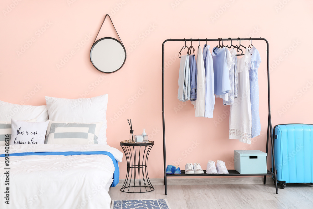 Interior of stylish bedroom with clothes rack