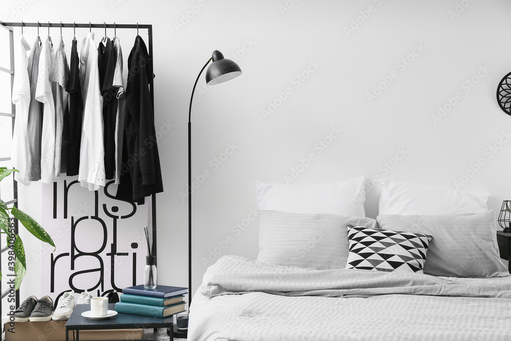 Interior of stylish bedroom with clothes rack