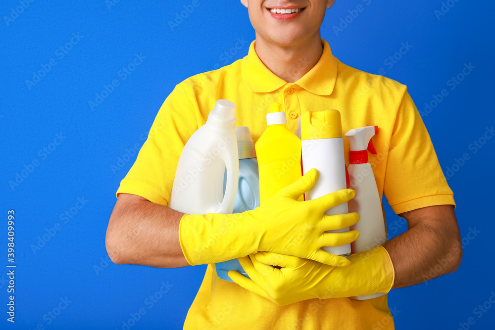 Young man with cleaning supplies on color background