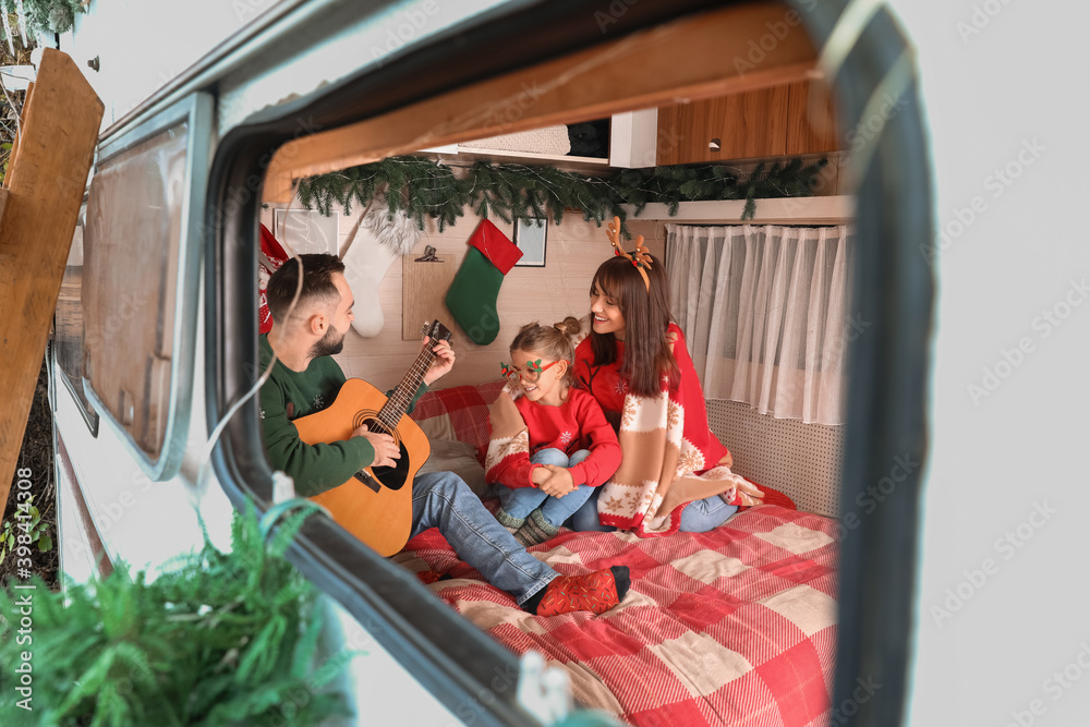 Happy family with guitar in motorhome on Christmas eve