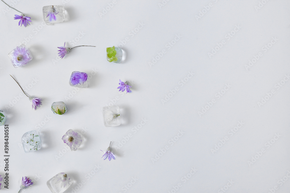 Beautiful flowers frozen in ice on light background