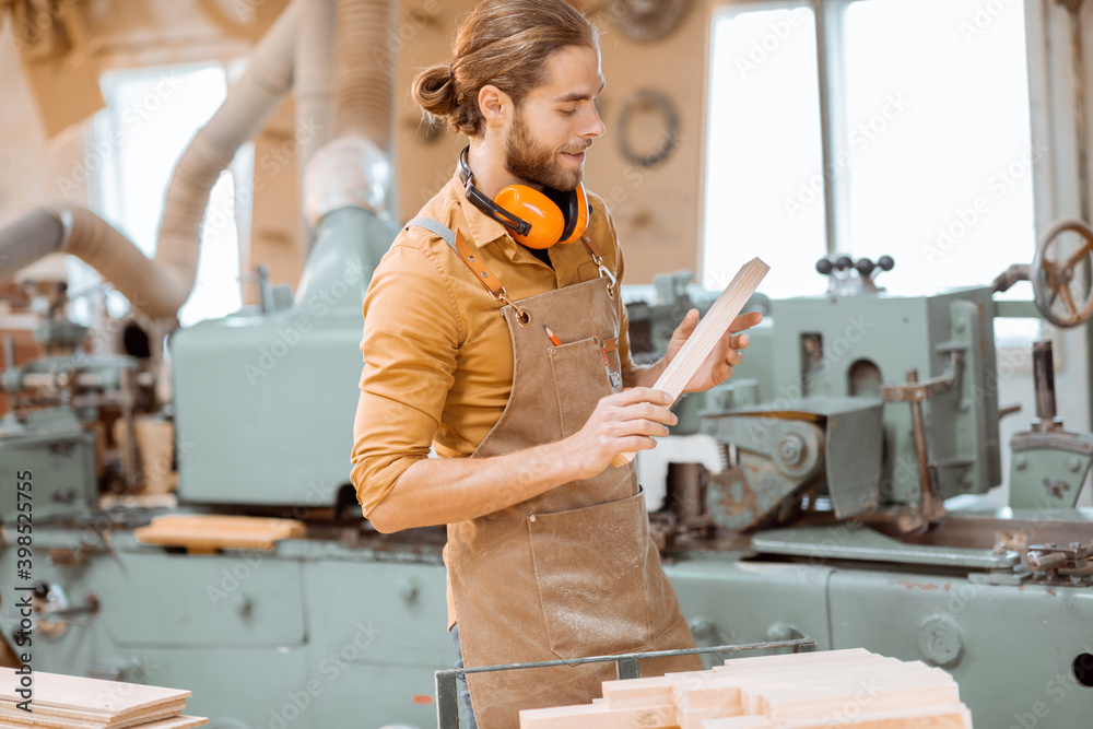 A carpenter works on a woodworking machine, holding cutter at the workshop