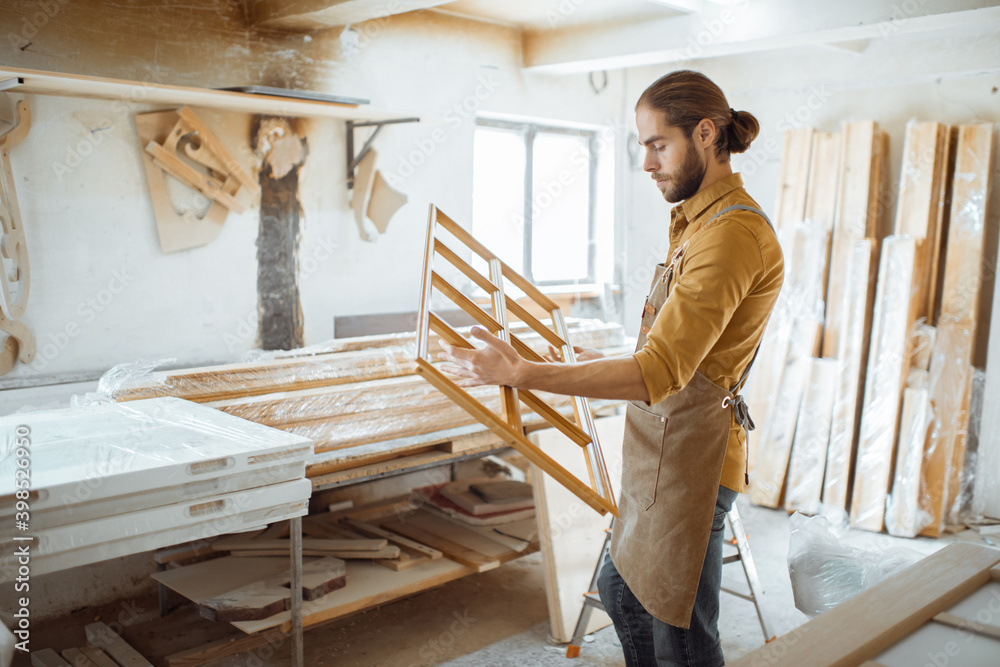 Handsome carpenter checking the quality of the window frame before the paint at the carpentry worksh