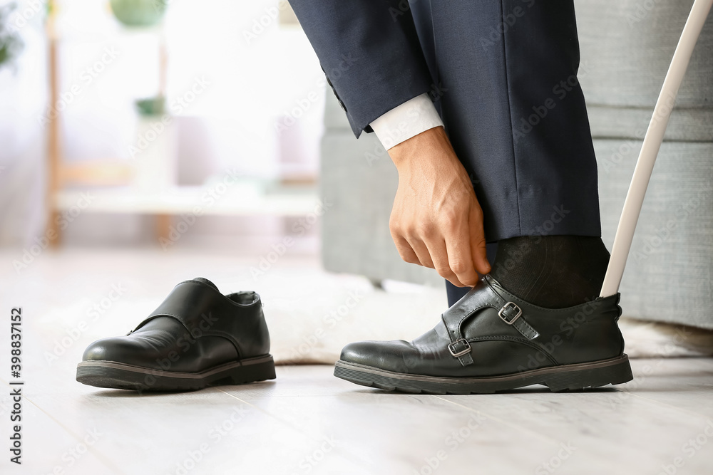 Young man putting on stylish shoes