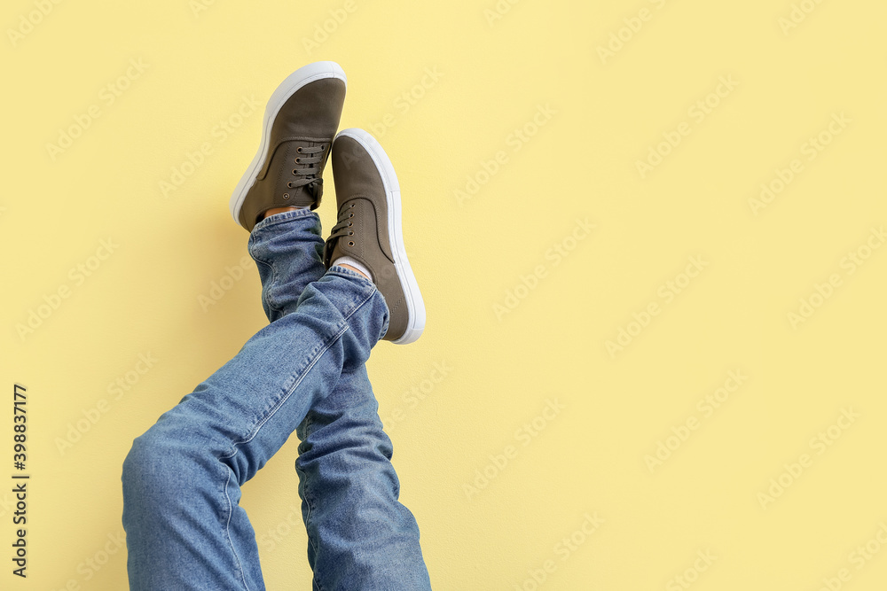 Young man in stylish shoes on color background