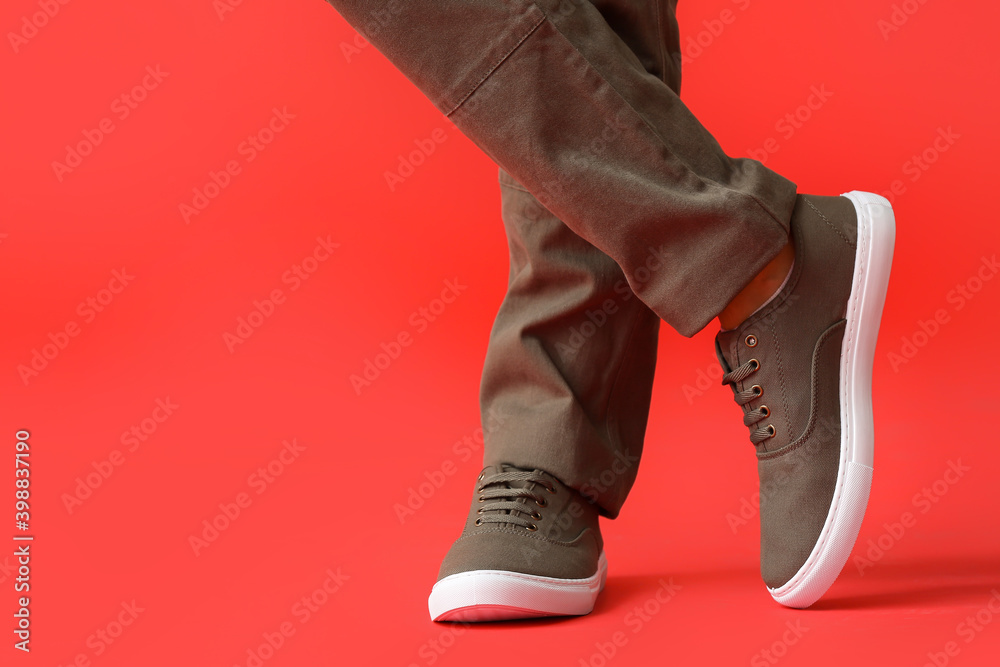 Young man in stylish shoes on color background