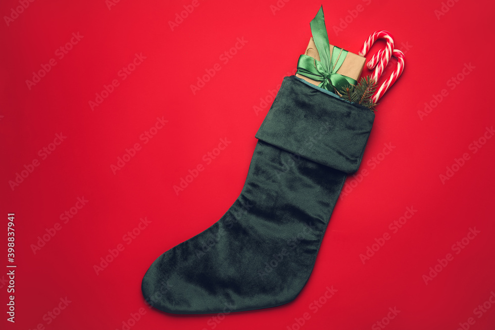 Christmas sock with gifts on color background