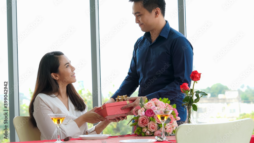 Romantic couple giving gift to lover at restaurant . Happy couple lifestyle .